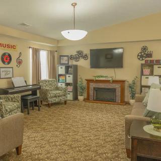 A cozy living room featuring a fireplace, piano, and comfortable seating.