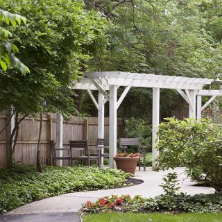 A serene garden with a white pergola and a winding pathway surrounded by lush greenery.