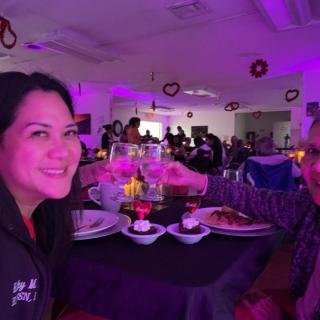 Two people enjoying a meal together in a dimly lit, festive restaurant setting.