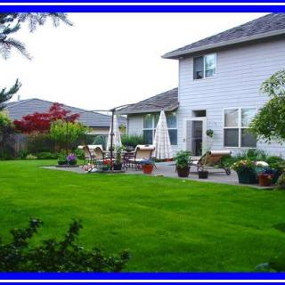 A well-maintained backyard with a green lawn and patio area.