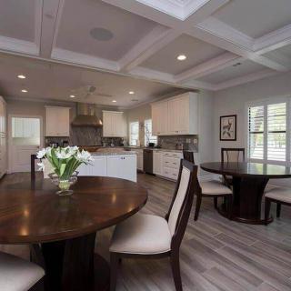 A modern dining area with an adjoining kitchen featuring elegant furniture and contemporary lighting.
