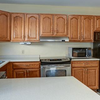 A kitchen with wooden cabinets, a stove, and a countertop.