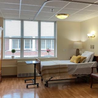 A well-lit hospital room featuring a patient bed and a view outside.