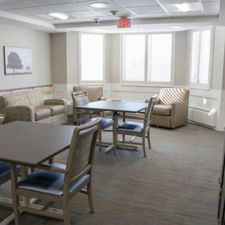 A cozy lounge area with tables, chairs, and sofas near large windows.