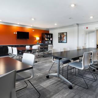 Modern conference room with sleek furniture and a vibrant orange accent wall.