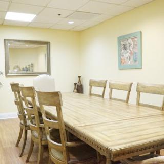 A spacious meeting room featuring a wooden conference table surrounded by chairs, designed for collaborative discussions.