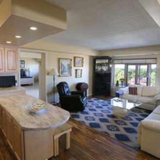 A cozy living room with stylish furniture and large windows, featuring a comfortable sofa, armchair, and a decorative rug.