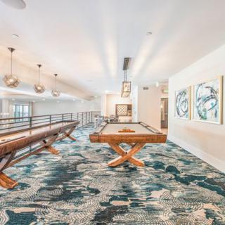 A modern game room featuring shuffleboard and pool tables with stylish decor and artwork.
