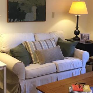 A cozy living room with a sofa, cushions, and a warm lamp.