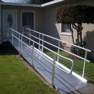 A wheelchair ramp with railings leading to the front door of a house, enhancing accessibility.