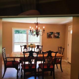 A dining room with a wooden table set, chairs, and a chandelier.