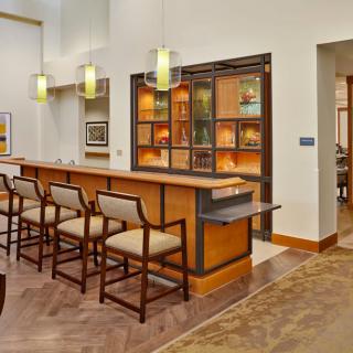 A modern bar interior with wooden chairs and a well-lit counter area.