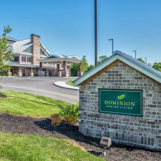 View of a building with a brick entrance sign and landscaped surroundings.