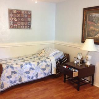 A cozy bedroom with a single bed, adorned with a decorative quilt and accompanied by a nightstand holding a lamp and an alarm clock.