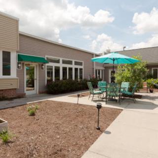 A sunny outdoor patio area with seating and umbrellas next to a building.