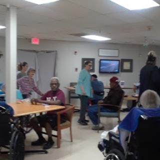 A lively common area in a senior living facility where residents engage with staff and each other.
