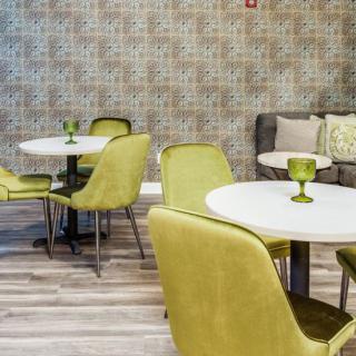 A modern cafe interior with yellow chairs and white tables, featuring a stylish wall design and wooden flooring.
