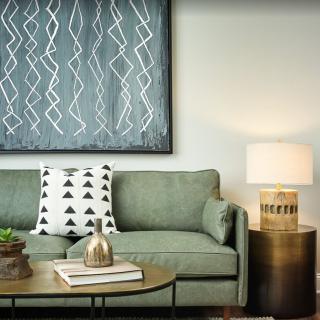 A modern living room with a green sofa, geometric cushion, and stylish decor.