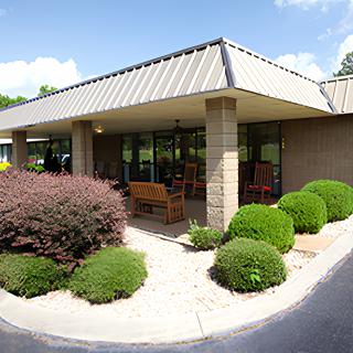 A well-maintained building entrance with landscaping and a sidewalk on a sunny day.