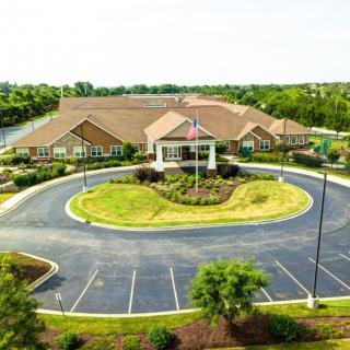 Aerial view of a suburban building with a circular driveway and landscaped surroundings.