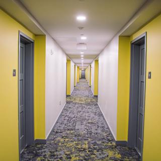 A brightly lit hallway with yellow walls and multiple doors.