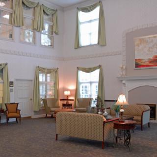 A spacious and elegantly decorated lounge area featuring comfortable seating and large windows.
