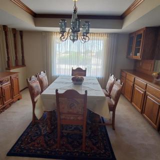A spacious dining room with a table, chairs, and a chandelier.