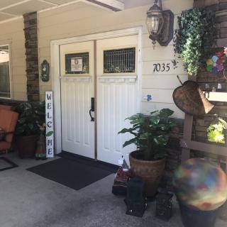 A welcoming front porch with double doors, surrounded by potted plants and cozy outdoor decorations.