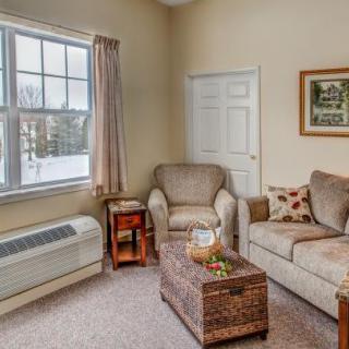Cozy living room with a sofa, armchair, and a window view.