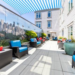 A stylish rooftop terrace with blue seating and vibrant planters, perfect for relaxing in an urban environment.