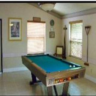 A cozy game room featuring a pool table, with natural light streaming in through two windows.