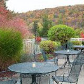 A scenic outdoor patio with tables and chairs, surrounded by vibrant autumn foliage.