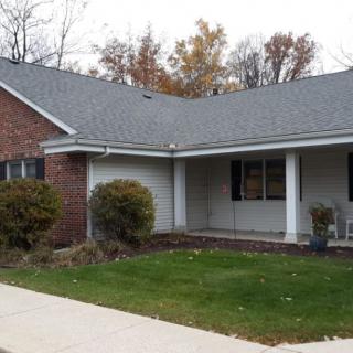 A suburban single-story brick house with a porch and a small front yard.
