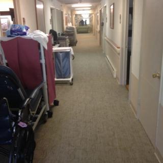 A hospital corridor with medical equipment and trolleys along the sides.