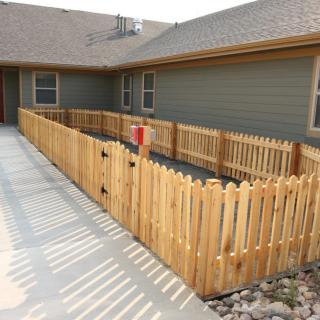 A wooden fence encloses a small yard in front of a house.