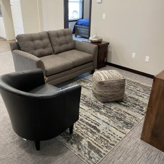 A cozy living room setup featuring a sofa, armchair, and a rug.