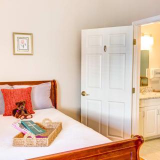 A cozy bedroom with a neatly made bed, featuring pillows and a tray, adjacent to an open door leading to a bathroom.