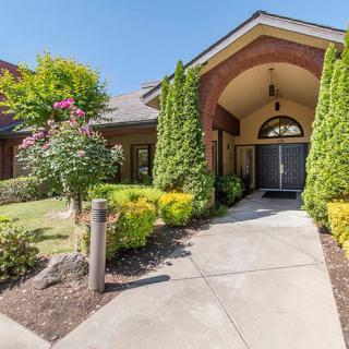 A welcoming entrance to a building with neatly landscaped gardens and a paved pathway.