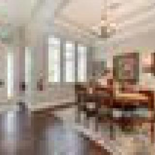 A well-lit dining room with hardwood flooring, featuring a central dining table and a chandelier.