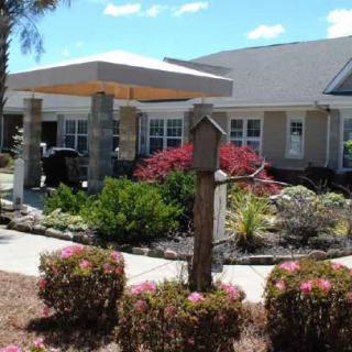 A well-maintained residential building with colorful gardens under a clear blue sky.