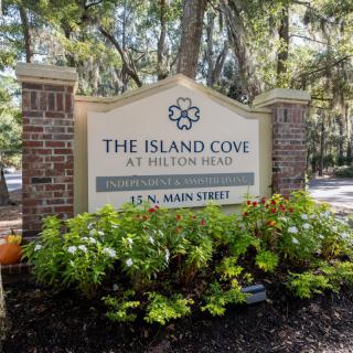 Entrance sign for The Island Cove at Hilton Head, surrounded by greenery and brick columns.