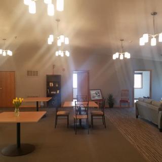 A warmly lit room with tables, chairs, and a sofa arranged for a cozy atmosphere.