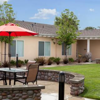 A peaceful backyard with patio furniture and a red umbrella offering shade.