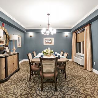 A beautifully decorated dining room featuring a central table with chairs, a chandelier, and elegant decor.