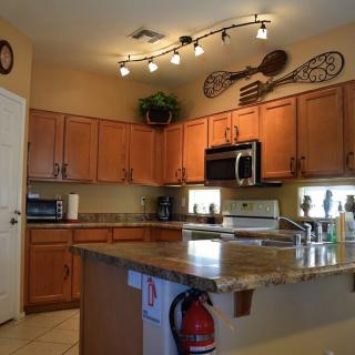 A cozy kitchen with wooden cabinets, modern appliances, and decorative lighting.