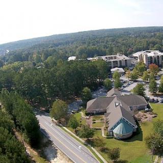 An aerial view showcasing a serene landscape with residential buildings surrounded by lush greenery and a winding road.