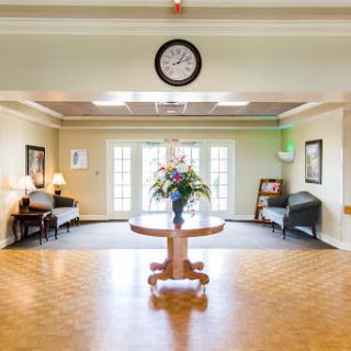 A bright and inviting lobby featuring a floral centerpiece, comfortable seating, and large windows that allow natural light to fill the space.