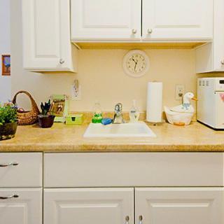 A tidy kitchen with white cabinets, a sink, and various appliances on the countertop.