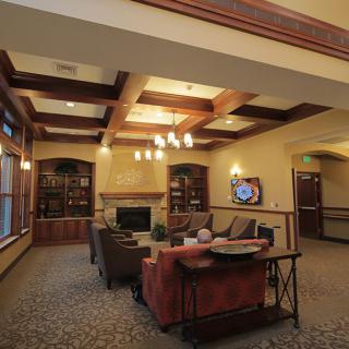 A cozy living room with a coffered ceiling, chandelier, and comfortable seating facing a television.