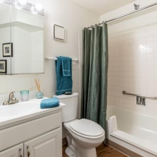 A clean and modern bathroom featuring a sink, toilet, and shower with a green curtain.